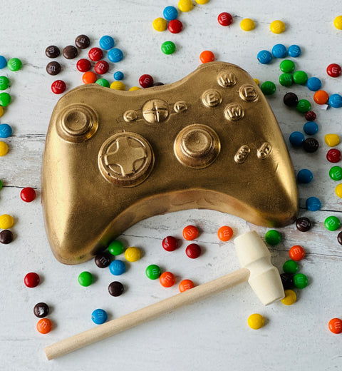 a gold game controller surrounded by candy and candies